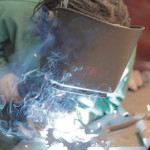 A student welds a bike path sculpture in a STAND affiliated project.